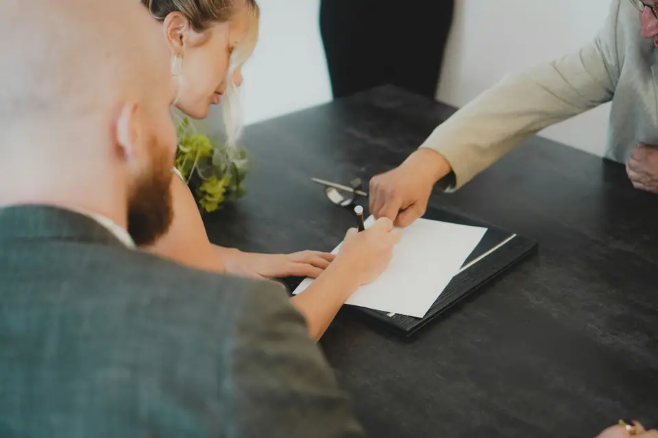 A couple signing a document across a desk