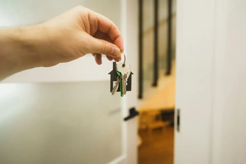 A hand holding house keys at an open front door